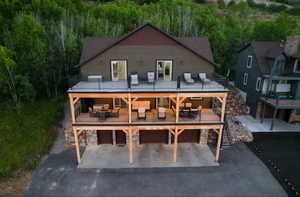 Back of house with stone siding, a patio, an attached garage, and driveway
