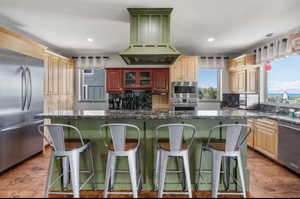 Kitchen featuring a breakfast bar, built in appliances, and green cabinetry