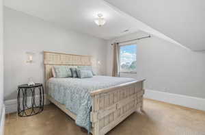 Bedroom with lofted ceiling and light carpet