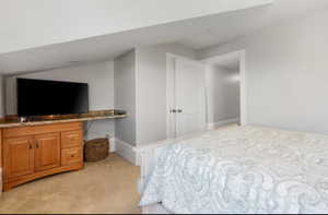 Bedroom featuring light colored carpet and vaulted ceiling
