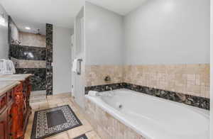 Full bath with vanity, a jetted tub, a walk in shower, stone tile flooring, and recessed lighting