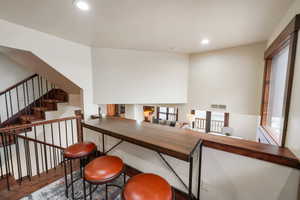 Bar area with wood counters, dark wood-type flooring, recessed lighting, and a high ceiling