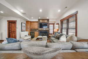 Living room featuring beverage cooler, a fireplace, wood finished floors, and recessed lighting