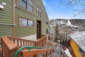 Snow covered deck with a mountain view and stairway