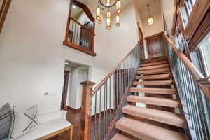 Stairs featuring wood-type flooring, a chandelier, and a high ceiling