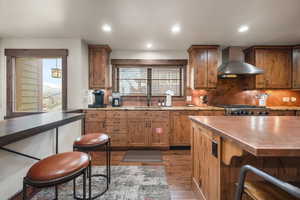 Kitchen with a kitchen breakfast bar, light wood finished floors, backsplash, wood finish cabinets, and plenty of natural light