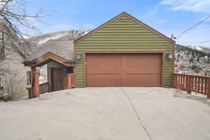 View of front of house featuring a garage, a mountain view, roof with shingles, and concrete driveway