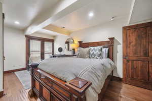 Bedroom featuring light wood-type flooring, french doors, beam ceiling, and recessed lighting