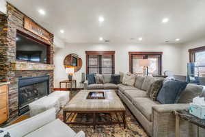 Living room with a stone fireplace and recessed lighting