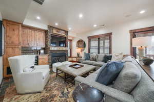 Living room featuring a stone fireplace and recessed lighting