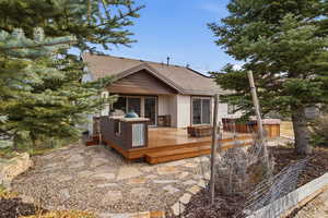 Back of property with roof with shingles, roof mounted solar panels, stucco siding, and a deck