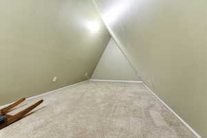 Additional living space featuring lofted ceiling and carpet floors
