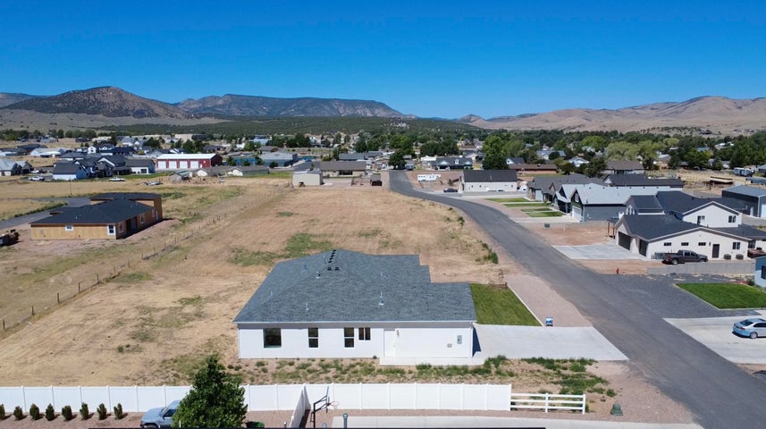 Newly constructed single-story residence featuring a gray shingle roof, white exterior siding, a concrete driveway, and a partially landscaped front yard