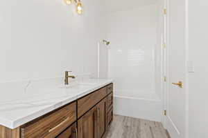 Full bathroom with vanity, light wood-type flooring, and bathtub / shower combination