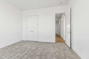 Unfurnished bedroom with light carpet and a closet