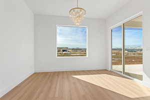 Unfurnished dining area featuring a chandelier and light wood-type flooring