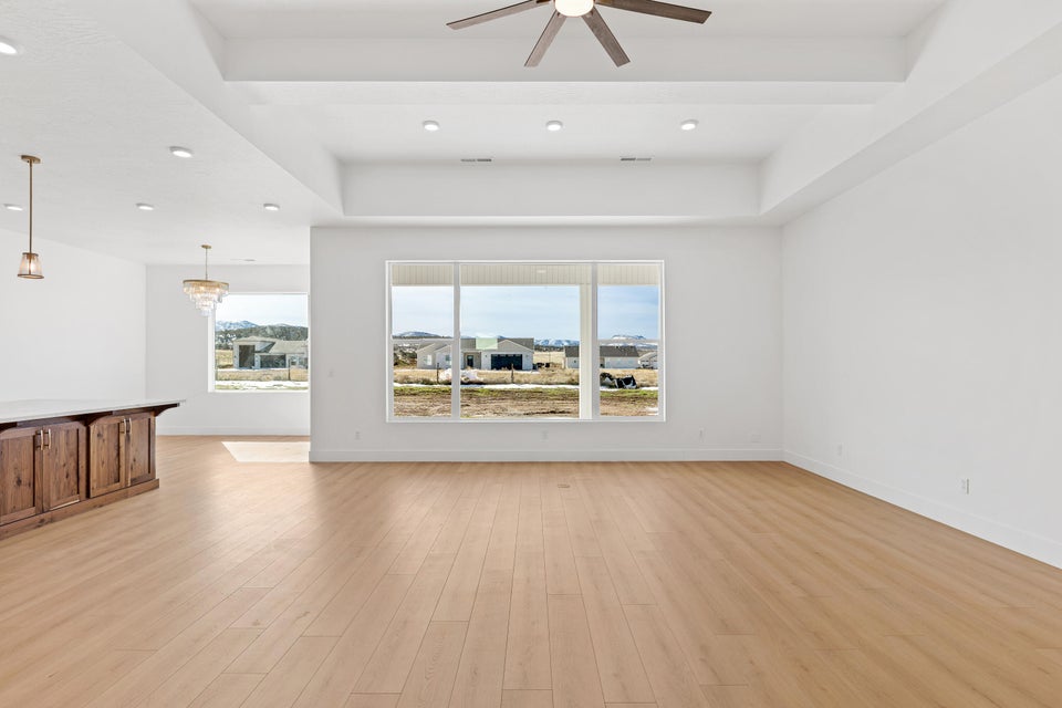 Unfurnished room featuring plenty of natural light, ceiling fan, light wood-style floors, a raised ceiling, and recessed lighting