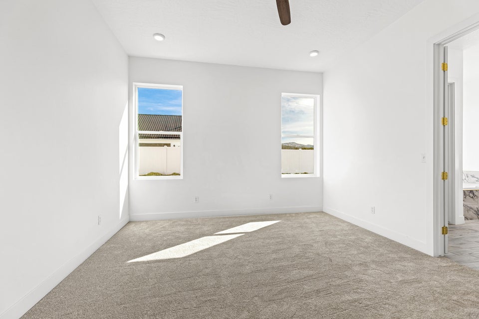 Carpeted spare room with ceiling fan and baseboards