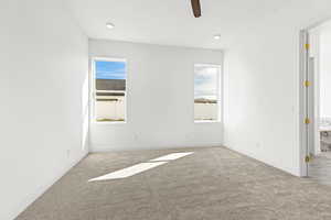 Carpeted spare room with ceiling fan and baseboards
