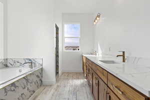 Bathroom featuring double vanity, light wood-type flooring, a garden tub, and a marble finish shower