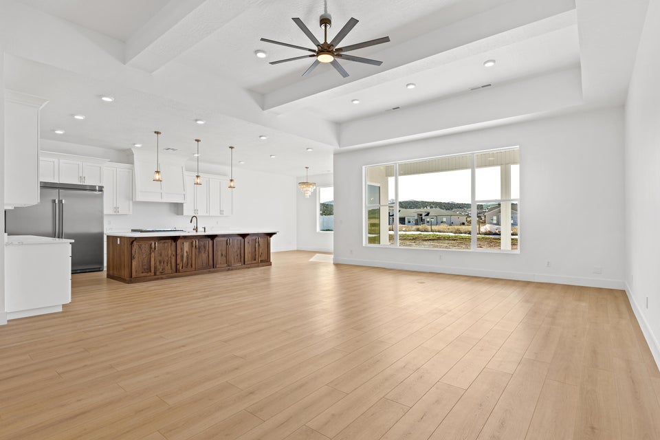 Unfurnished living room with beamed ceiling, a ceiling fan, light wood-style flooring, and recessed lighting