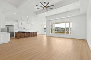 Unfurnished living room with beamed ceiling, a ceiling fan, light wood-style flooring, and recessed lighting