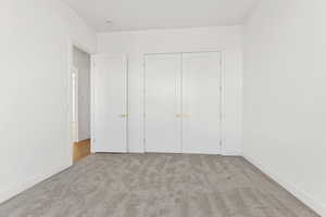 Unfurnished bedroom featuring light colored carpet and a closet
