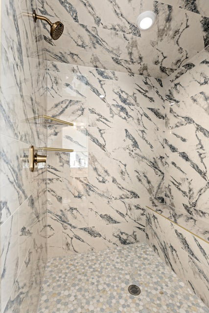 Full bath with a marble finish shower