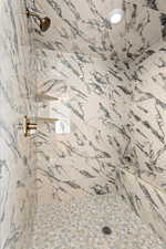 Full bath with a marble finish shower