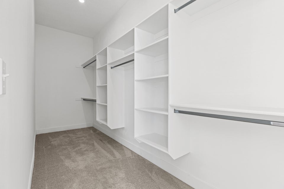 Walk in closet featuring light colored carpet