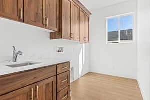 Laundry area with washer hookup, cabinet space, and light wood-type flooring