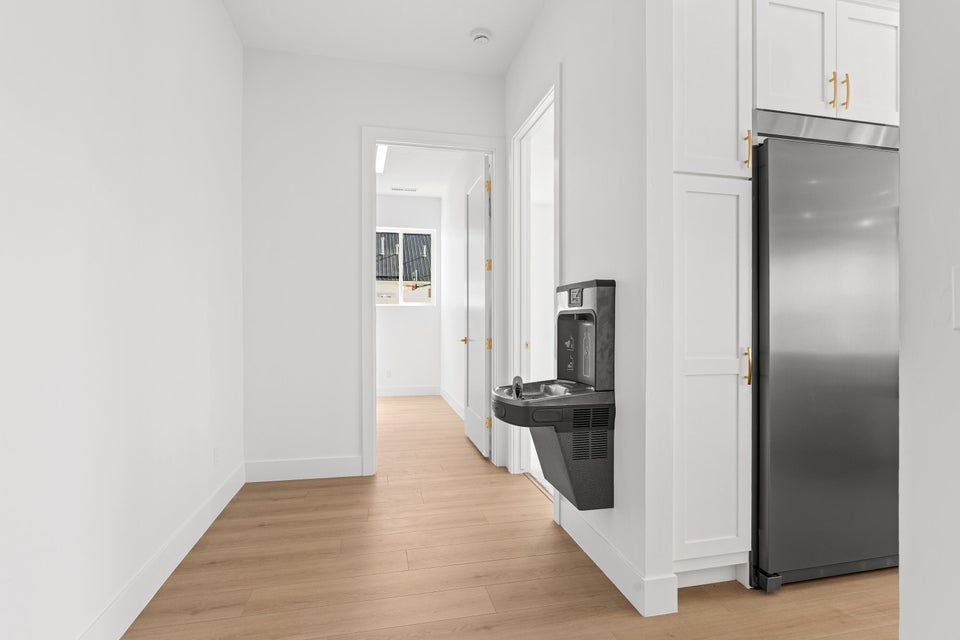 Kitchen with stainless steel refrigerator, light wood-type flooring, and white cabinetry