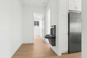 Kitchen with stainless steel refrigerator, light wood-type flooring, and white cabinetry