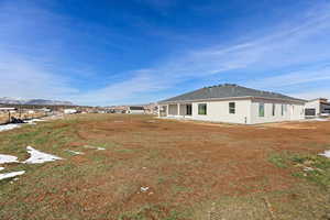 Rear view of property with a patio, a shingled roof, a mountain view, and stucco siding