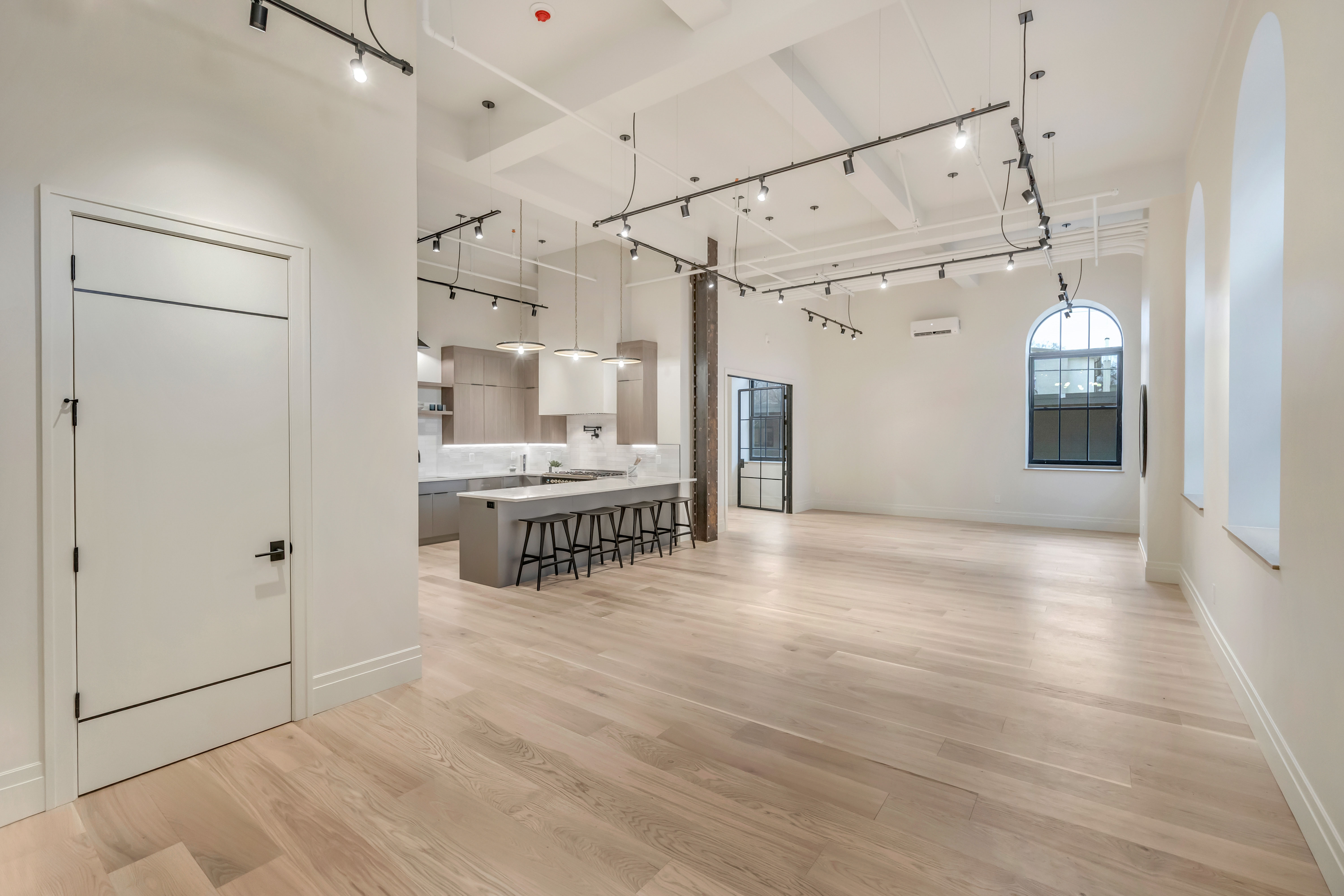 Living area with rail lighting, light wood-style floors, and a high ceiling