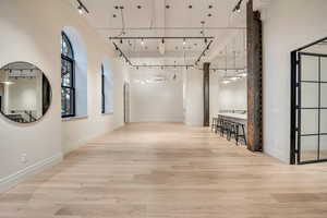 Hall with a high ceiling, light wood-type flooring, and track lighting