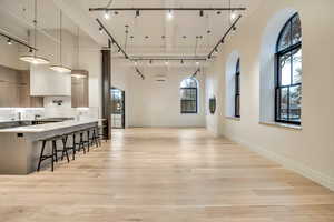 Dining area featuring rail lighting, a high ceiling, and light wood finished floors