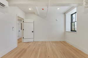 Spare room with a wall mounted mini split, light wood-style flooring, and recessed lighting