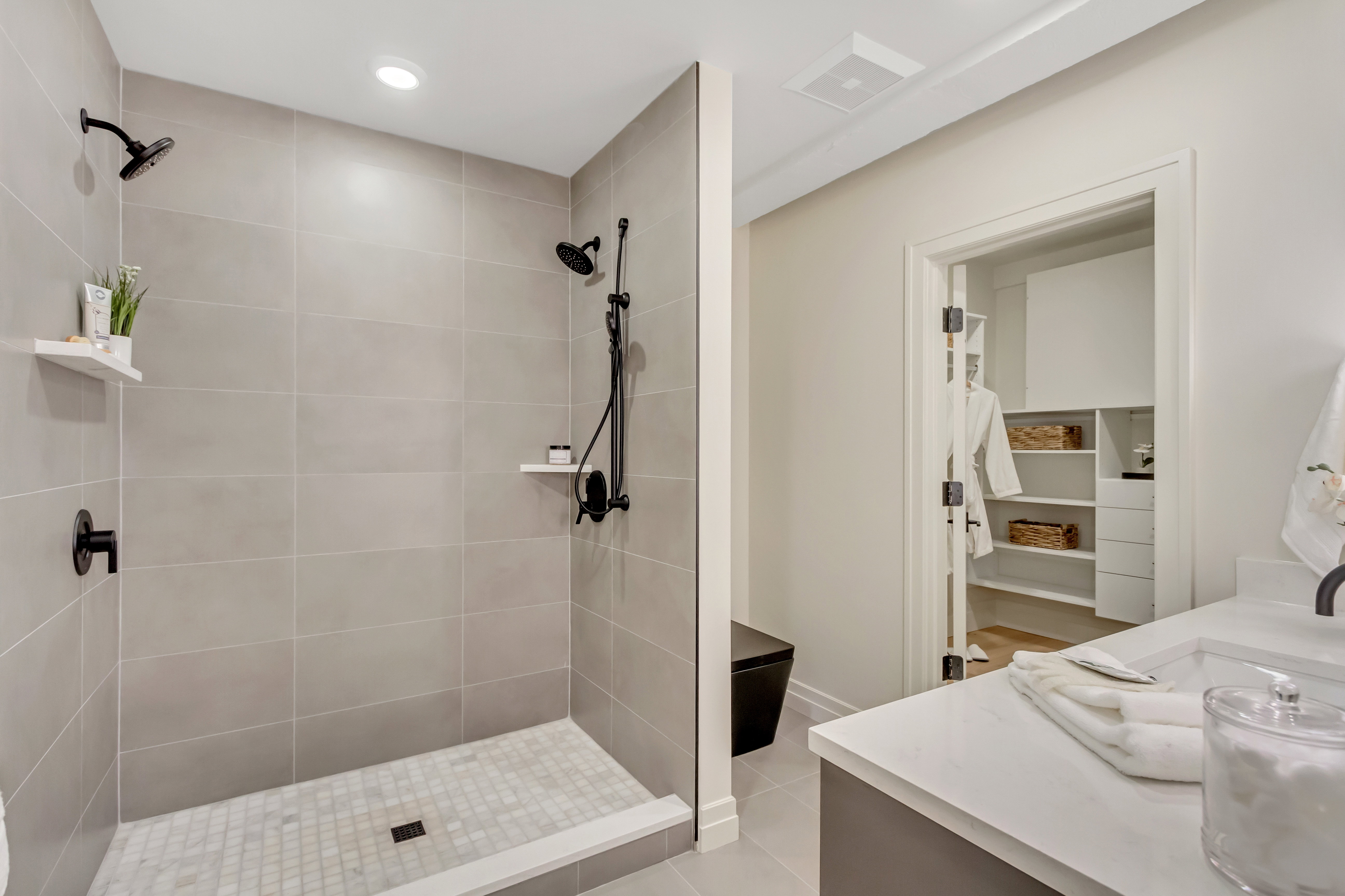 Full bath featuring vanity, a tile shower, light tile patterned flooring, recessed lighting, and a spacious closet