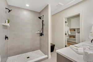 Full bath featuring vanity, a tile shower, light tile patterned flooring, recessed lighting, and a spacious closet