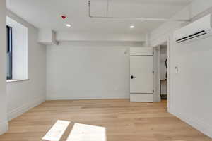 Basement featuring light wood-style floors, recessed lighting, and a mini split for heating / cooling
