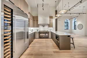 Kitchen featuring a peninsula, a breakfast bar, backsplash, high end appliances, and light wood-type flooring