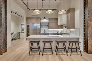 Kitchen featuring a peninsula, a high ceiling, a kitchen bar, light stone counters, and tasteful backsplash