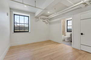 Unfurnished bedroom with light wood-style floors, multiple windows, recessed lighting, and ensuite bathroom