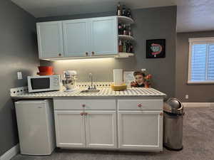 Kitchen with fridge, light countertops, open shelves, white cabinetry, and white microwave