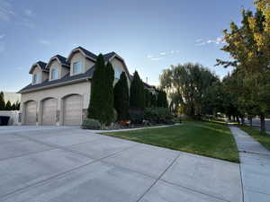 View of home's exterior with stucco siding, driveway, a yard, and stone siding