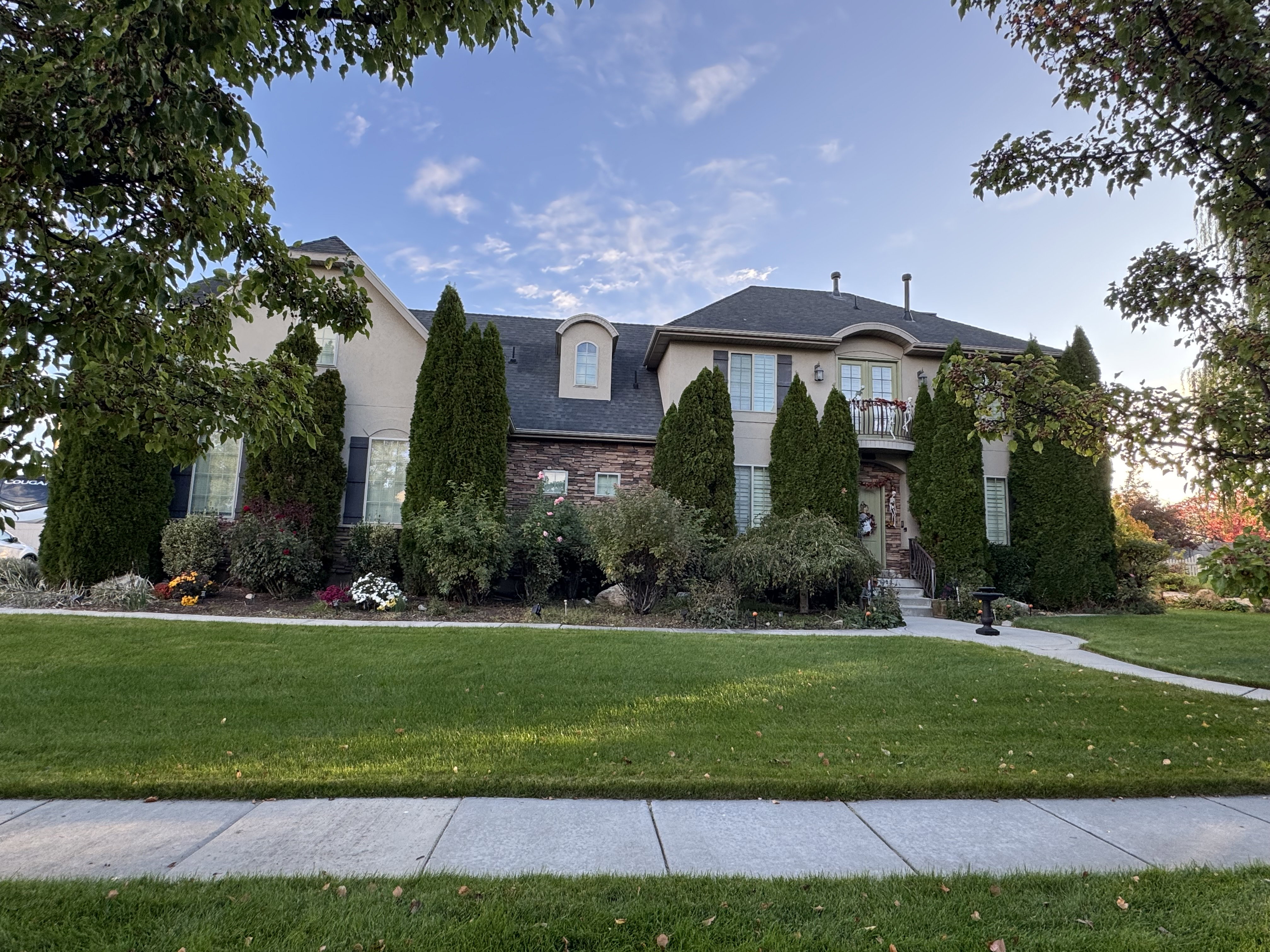 French country home featuring a front yard, stone siding, and stucco siding