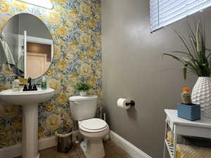 Half bath featuring light tile patterned floors and wallpapered walls