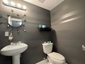Half bath featuring toilet and a textured ceiling