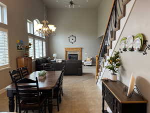 Dining room featuring a glass covered fireplace, a high ceiling, light tile patterned floors, and a chandelier